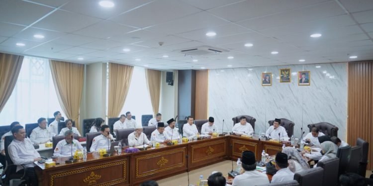 BANDAR LAMPUNG – Universitas Islam Negeri (UIN) Raden Intan Lampung (RIL) menegaskan langkah penajaman program dan keberlanjutan kinerja tahun 2026 melalui penandatanganan kontrak kinerja Indikator Kinerja Utama (IKU) dan penyerahan Rencana Kerja Tahunan (RKT) oleh seluruh pimpinan bersama Rektor, disaksikan para wakil rektor, Senin (04/05/2026) di Ruang Rapat Rektor.Agenda ini merupakan tindak lanjut dari Rapat Kerja Pimpinan (Rakerpim) 19 April 2026. Rekomendasi raker tersebut diterjemahkan kembali dalam arah kebijakan yang lebih operasional, terutama terkait penajaman anggaran, efisiensi, serta fokus program prioritas kampus.Wakil Rektor II UIN Raden Intan Lampung, Prof. Dr. Safari, M.Sos.I, menjelaskan bahwa kebijakan penajaman (efisiensi) anggaran tahun 2026 mengacu pada kebijakan pemerintah pusat tentang penataan belanja satuan kerja serta rekomendasi rapat kerja 19 April 2026.Ia menegaskan, anggaran 2026 diarahkan pada program-program strategis yang memiliki dampak langsung terhadap target universitas“Anggaran ini menjadi stimulan. Karena itu harus difokuskan pada kegiatan prioritas strategis,” ujar Prof. Safari.Program prioritas yang dimaksud antara lain mendukung pendirian Fakultas Kedokteran, menunjang upaya mempertahankan akreditasi perguruan tinggi (APT) Unggul, termasuk kebutuhan sertifikasi dan pemeringkatan internasional, serta peningkatan jumlah mahasiswa baru.Selain itu, rapat juga membahas penyatuan gedung pascasarjana agar fasilitas yang ada dapat terintegrasi dan lebih efisien.Di bidang efisiensi, Prof. Safari meminta seluruh unit melaporkan dampak nyata dari kebijakan penghematan, terutama terkait penggunaan listrik dan air serta optimalisasi fasilitas kampus menjadi bagian dari kebijakan baru pola kerja.“Harus ada statistiknya. Jangan hanya kebijakan kerja dari rumah, tapi tidak terukur dampaknya. Tujuan pola kerja itu untuk penghematan energi,” ujarnya.Sementara itu, Rektor UIN Raden Intan Lampung Prof. H. Wan Jamaluddin Z, M.Ag., Ph.D. mengingatkan seluruh pimpinan agar tetap menjaga semangat kerja di tengah kondisi anggaran yang mengalami penyesuaian.“Apapun itu kita tetap harus bersyukur kepada Allah SWT. Saya berharap kita semua tetap bisa menjaga, memelihara, bahkan meningkatkan semangat kinerja kita,” kata Rektor.Ia menegaskan, hak-hak dasar aparatur tidak terganggu. “Gaji, tunjangan kinerja, sertifikasi insya Allah tetap berjalan,” ujarnya.Karena itu, menurut Rektor, penyesuaian anggaran tidak boleh menjadi alasan menurunnya kinerja. Ia mengajak seluruh sivitas akademika mengikuti arahan pemerintah terkait pola kerja baru dengan semangat hidup lebih sederhana.Rektor menilai semangat efisiensi harus tercermin dalam kehidupan kampus sehari-hari, mulai dari penghematan listrik, air, hingga penggunaan kendaraan operasional.Rektor melanjutkan, kampus perlu mengoptimalkan aset serta membuka peluang sumber pendanaan eksternal yang dapat menopang pelaksanaan tridarma perguruan tinggi dan pengembangan kampus.Ia juga menaruh perhatian pada mahasiswa melalui skema beasiswa dan dukungan pembiayaan studi.“Tingkat kepedulian kita kepada mahasiswa bisa disiasati melalui reward atas capaian mereka, misalnya bantuan UKT yang langsung dibayarkan untuk mahasiswa yang bersangkutan. Itu lebih terukur dan mudah diawasi,” ujarnya.Rektor juga mengimbau pimpinan yang memiliki jejaring dengan dunia usaha, industri, dan pihak eksternal lainnya agar ikut membantu membuka peluang dukungan bagi mahasiswa dan alumni, terutama untuk membantu penyelesaian studi dan keberlanjutan pengabdian pasca studi.Dalam kesempatan itu, Rektor kembali menegaskan pentingnya soliditas tim kerja.“Kita membutuhkan monoloyalitas dan soliditas tim kerja. Jangan mudah terpengaruh isu ini dan itu. Dengan tim baru ini saya menaruh kepercayaan yang sangat besar,” katanya.Prof Wan mengingatkan bahwa tantangan akreditasi dua tahun ke depan tidak ringan. Karena itu, seluruh unit diminta mulai menyiapkan dokumen berbasis data faktual sejak sekarang.“Kalau dicicil dari sekarang, dua tahun ke depan seluruh kebutuhan dokumen sudah siap,” ujarnya.Rektor juga menaruh harapan pada tim baru agar menghadirkan terobosan-terobosan baru bagi kemajuan UIN Raden Intan Lampung.“Apapun situasi dan kondisi yang kita hadapi, kita harus siap. Optimisme harus tetap tinggi. Alhamdulillah UIN Raden Intan Lampung masih bisa beradaptasi,” katanya.Kegiatan kemudian dilanjutkan dengan penandatanganan Kontrak Kinerja IKU dan penyerahan RKT Tahun 2026 oleh seluruh pimpinan kepada Rektor, disaksikan para Wakil Rektor.Langkah penajaman program, efisiensi anggaran, dan penguatan kinerja tahun 2026 ini juga menjadi bagian dari keberlanjutan arah kepemimpinan Rektor UIN Raden Intan Lampung dalam periode Ber-ISI Mendunia, yang menekankan penguatan institusi, daya saing internasional, serta keberlanjutan pengembangan kampus.[De]