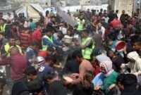 Warga Palestina menerima makanan gratis dari pusat distribusi makanan di Gaza City . [Xin]