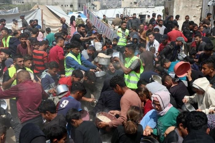 Warga Palestina menerima makanan gratis dari pusat distribusi makanan di Gaza City . [Xin]