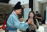 Seorang staf dari Tiongkok sedang membimbing warga Indonesia memainkan replika Suling Tulang Jiahu, di Jakarta. (Xinhua)
