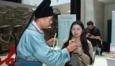 Seorang staf dari Tiongkok sedang membimbing warga Indonesia memainkan replika Suling Tulang Jiahu, di Jakarta. (Xinhua)