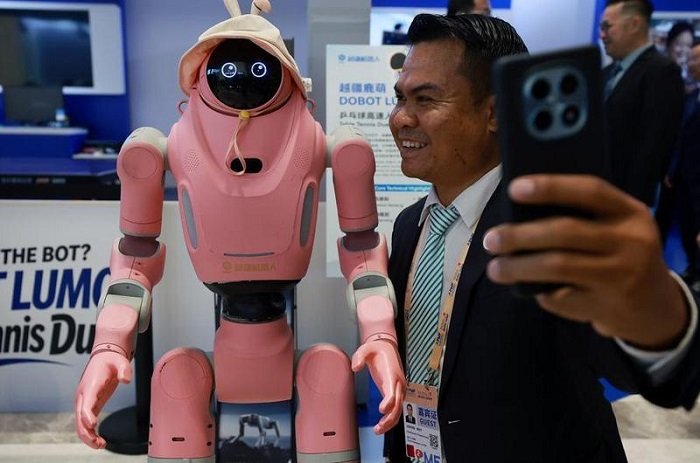 Seorang pengunjung berswafoto bersama robot dalam Forum Media Asia-Pasifik di Shenzhen, Provinsi Guangdong, Tiongkok selatan, pada 5 September 2026. (Xinhua)