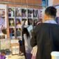 
Foto dokumentasi ini menunjukkan seorang wisatawan menjajal syal batik di sebuah stan pasar rakyat di Chongqing, Tiongkok barat daya. (Xinhua)