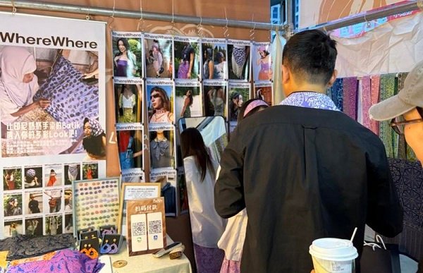 Foto dokumentasi ini menunjukkan seorang wisatawan menjajal syal batik di sebuah stan pasar rakyat di Chongqing, Tiongkok barat daya. (Xinhua)
