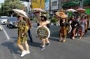 SEJUMLAH perempuan yang mengenakan baju batik dan membawa payung bermotif batik melakukan peragaan busana saat peringatan Hari Batik Nasional di sebuah penyeberangan jalan di sekitar lampu lalu lintas Jalan Slamet Riyadi di Kota Solo, Provinsi Jawa Tengah, pada 2 Oktober 2026. (Xinhua)