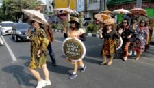 SEJUMLAH perempuan yang mengenakan baju batik dan membawa payung bermotif batik melakukan peragaan busana saat peringatan Hari Batik Nasional di sebuah penyeberangan jalan di sekitar lampu lalu lintas Jalan Slamet Riyadi di Kota Solo, Provinsi Jawa Tengah, pada 2 Oktober 2026. (Xinhua)