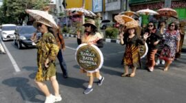 SEJUMLAH perempuan yang mengenakan baju batik dan membawa payung bermotif batik melakukan peragaan busana saat peringatan Hari Batik Nasional di sebuah penyeberangan jalan di sekitar lampu lalu lintas Jalan Slamet Riyadi di Kota Solo, Provinsi Jawa Tengah, pada 2 Oktober 2026. (Xinhua)