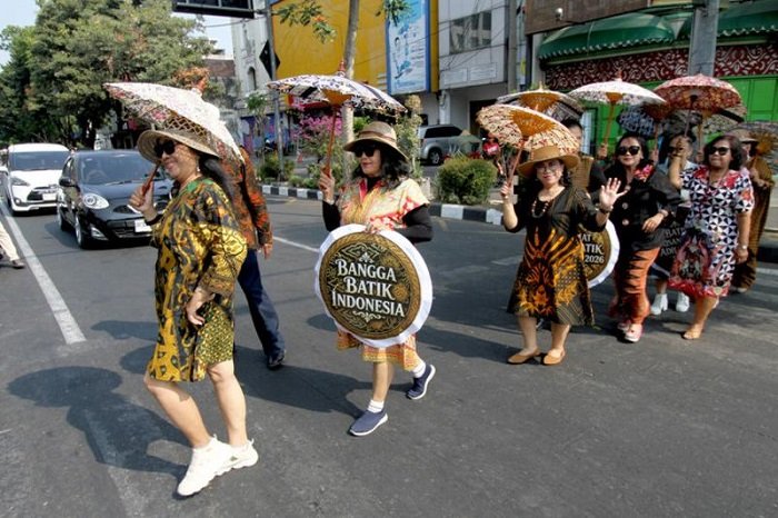 SEJUMLAH perempuan yang mengenakan baju batik dan membawa payung bermotif batik melakukan peragaan busana saat peringatan Hari Batik Nasional di sebuah penyeberangan jalan di sekitar lampu lalu lintas Jalan Slamet Riyadi di Kota Solo, Provinsi Jawa Tengah, pada 2 Oktober 2026. (Xinhua)