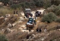 Para petani Palestina terlihat di sebuah pos pemeriksaan militer Israel setelah pasukan tersebut mencegah mereka memanen zaitun di lahan mereka, di Desa Salem, sebelah timur Nablus, di Tepi Barat, pada 17 Oktober 2026. (Xinhua)