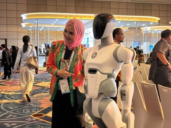 Seorang peserta Danantara Technology Innovation Investment Forum (DTIIF) 2026 berfoto dengan salah satu robot buatan AI² Robotics di Jakarta pada 28 Oktober 2026. (Xinhua/Ni Luh Anggela De Merici S.)